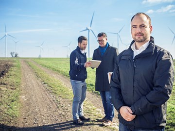 Frank Eberlein von envia THERM steht mit 2 weiteren Männern auf einem Feldweg vor zahlreichen Windkrafträdern Frank Eberlein von envia THERM steht mit 2 weiteren Männern auf einem Feldweg vor zahlreichen Windkrafträdern