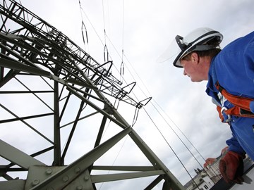 Mann blauer Overoll + Helm vor Hochspannungsmast Mann blauer Overoll + Helm vor Hochspannungsmast