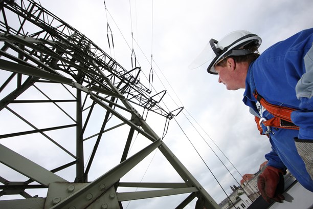 Mann blauer Overoll + Helm vor Hochspannungsmast Mann blauer Overoll + Helm vor Hochspannungsmast