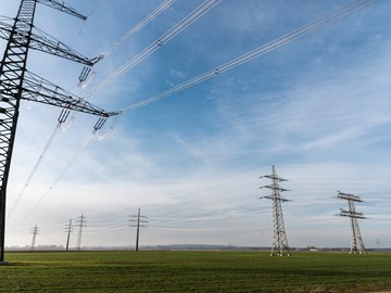 Strommasten auf einem grünen Feld Strommasten auf einem grünen Feld