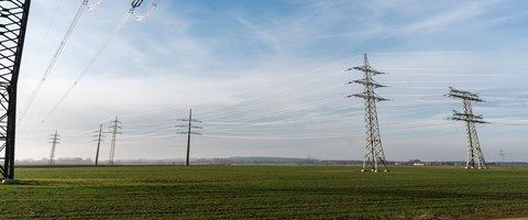 Strommasten auf einem grünen Feld Strommasten auf einem grünen Feld