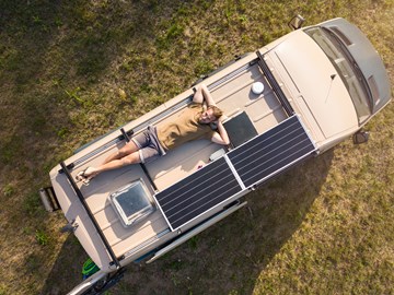 Mann liegt auf Dach eines Wohnmobiles mit Solarzellen. Mann liegt auf Dach eines Wohnmobiles mit Solarzellen.