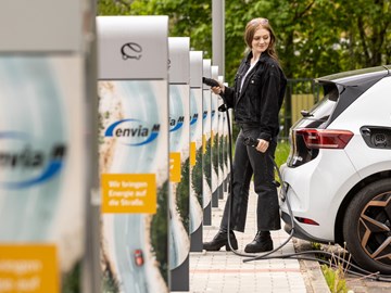 eine Frau steckt ein E-Auto zum Laden an eine Ladesäule an eine Frau steckt ein E-Auto zum Laden an eine Ladesäule an