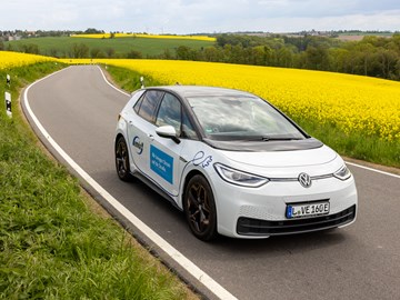 E-Auto fährt durch Rapsfeld E-Auto fährt durch Rapsfeld