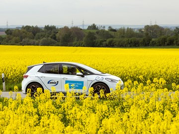 E-Auto fährt durch Rapsfeld E-Auto fährt durch Rapsfeld
