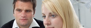 Junge Frau und junger Mann blicken interessiert auf einen PC-Bildschirm Junge Frau und junger Mann blicken interessiert auf einen PC-Bildschirm