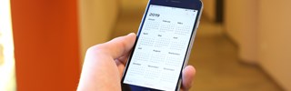 Hand mit Smartphone auf dem ein Kalender zu sehen ist Hand mit Smartphone auf dem ein Kalender zu sehen ist