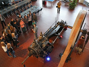 Schülergruppe besichtigt eine große historische Dampfmaschine Schülergruppe besichtigt eine große historische Dampfmaschine