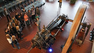 Schülergruppe besichtigt eine große historische Dampfmaschine Schülergruppe besichtigt eine große historische Dampfmaschine