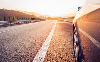 Auto fährt auf einer Straße in den Sonnenuntergang Auto fährt auf einer Straße in den Sonnenuntergang